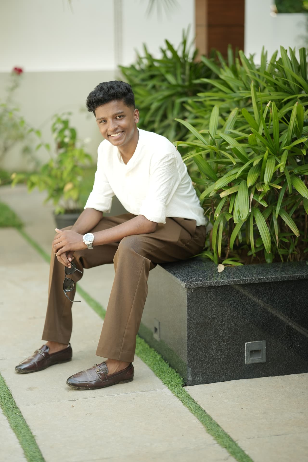 Anfas seated outdoors, smiling in a white shirt
